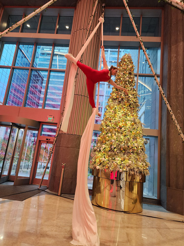 Woman performs with a christmas tree behind